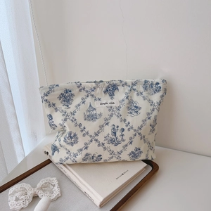 Close-up of beige canvas cosmetic bag with vintage blue toile de jouy print and simple wish label