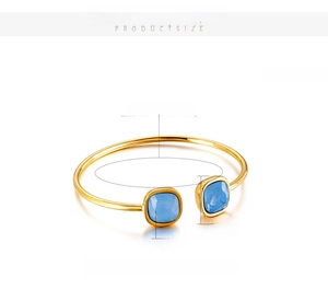 Detail view of golden stainless steel open bangle with blue glass gems and measurements