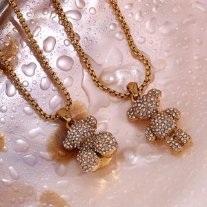 Macro detail of 18K gold plated bear pendants with sparkling crystals on pink surface