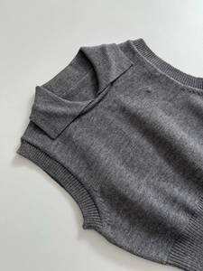 Detailed view of dark grey knitted vest featuring a lapel collar and ribbed hem texture