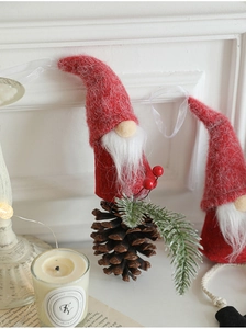 Close-up of a Christmas gnome ornament with red felt hat and a natural pine cone base
