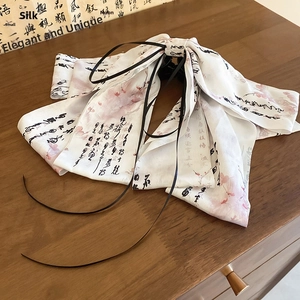 Detail of white ribbon hair claw with plum blossom print and elegant black tassels