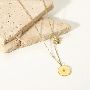 Detail of 18K gold plated stainless steel star pendant on beige textured stone base