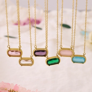 Golden necklaces with colorful rectangular zircon pendants displayed on white fabric