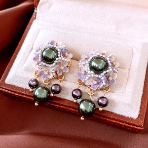 Detailed macro view of vintage emerald green pearl earrings with purple floral beadwork