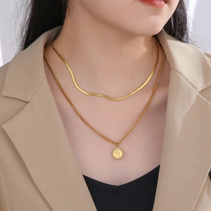 Detail of layered gold double necklace featuring flat snake chain and coin pendant