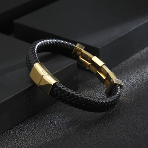 Close-up of black braided leather bracelet featuring a polished gold-toned metal clasp