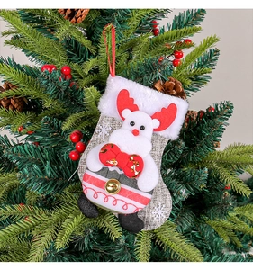 Close-up of a plush reindeer Christmas stocking with gold bells hanging on a tree