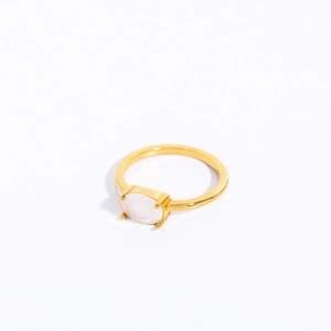 Detail of four-prong gold plated ring with oval pale pink gemstone on white background