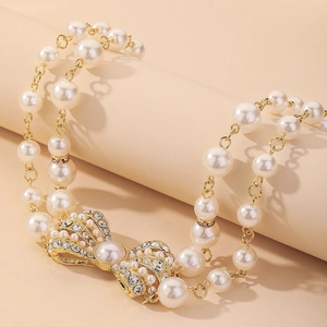 Dettaglio della collana di perle a doppio strato con ciondolo a fiocco di strass