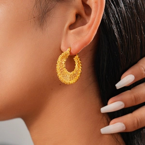 Close-up of 18k gold plated hollow woven mesh hoop earrings worn by a female model
