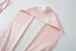 Macro shot of pink satin scarf detail showing smooth texture and edge stitching