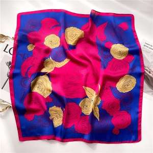 Close-up of royal blue silk scarf featuring vibrant rose patterns and premium rolled edges
