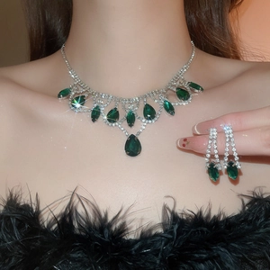 Close-up of green teardrop pendant necklace and earrings with sparkling diamond accents