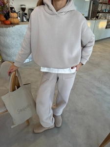 Detail van beige oversized hoodie en joggingbroek met grote opgestikte zakken aan de voorkant