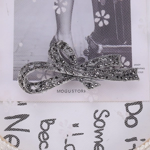 Dettaglio di spilla a fiocco vintage in argento con cristalli neri su sfondo retrò