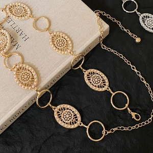 Close-up of golden metal waist chain with hollow oval links and inlaid white pearls