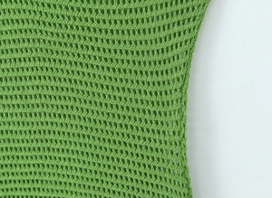 Dettaglio ravvicinato della trama all'uncinetto verde e della maglia di questo abito