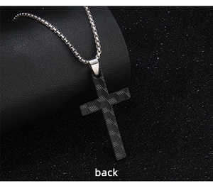 Macro view of black cross pendant showing textured geometric pattern on the back side