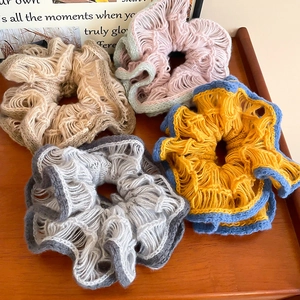 Detailed macro view of hollow knitted double-layer flower hair ties on a wooden tray