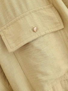 Vue macro du tissu tissé kaki avec bouton en métal et détail de poche à rabat