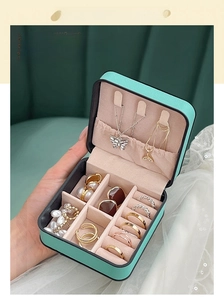 Handheld mint green portable jewelry box showing compact size and multi-compartment interior