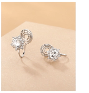 Macro detail of silver sunflower ear clips with sparkling cubic zirconia and soft clip pads