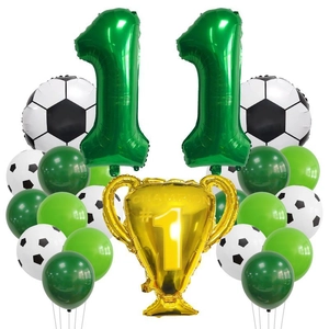 Detail of football party kit featuring golden champion trophy and green number 11 balloons