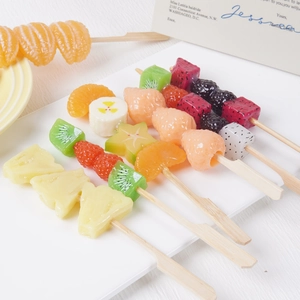 Realistic artificial fruit skewers model with strawberry and orange on a white plate