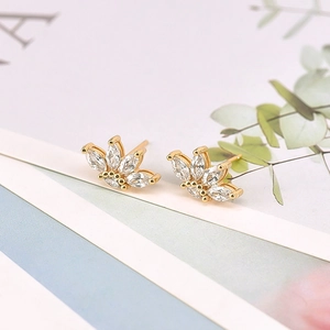 Dettaglio di orecchini a fiore dorati con zirconi marquise su una rivista patinata