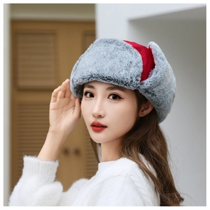 Detail of winter trapper hat with red fabric and thick grey faux fur ear flaps