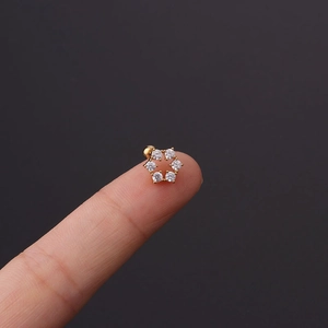 Close-up of a small floral zircon stud earring with a gold base held on a fingertip