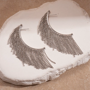 Detail shot of silver metallic beaded fringe earrings on a white stone texture base