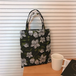 Detail shot of the embossed floral jacquard fabric on a black cotton tote bag