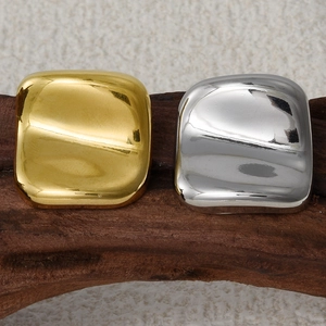 Macro shot of minimalist square stud earrings in gold and silver finish on wood