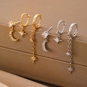 Detailed view of gold and silver star and moon earrings set with zircon stones