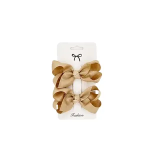 Detail showing a pair of khaki grosgrain ribbon hair bows on a white fashion card