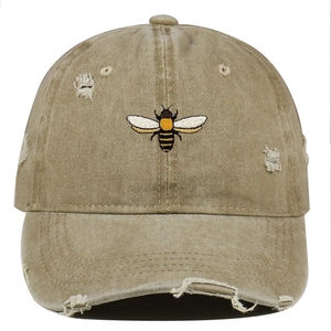 Close-up of bee embroidery detail on khaki washed distressed cotton baseball cap