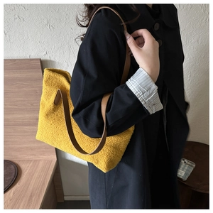 Detail of yellow plush tote bag showing soft fuzzy texture and brown leather straps