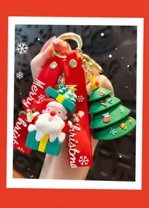 Gros plan d'un joli porte-clés Père Noël et sapin de Noël avec une dragonne rouge.