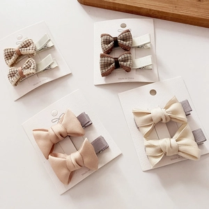 Set of eight assorted plaid and solid fabric bow hair clips displayed on white cards