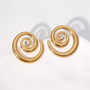 Golden spiral vortex stud earrings with centered sparkling crystals on a white display