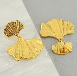 Macro detail of golden ginkgo leaf earrings showing intricate textured metal surface