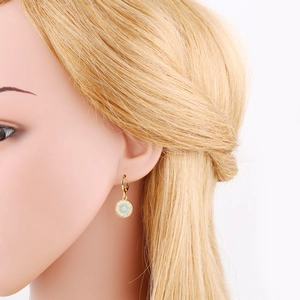 Detailed close-up of golden evil eye earrings with blue stone and white zircons on model
