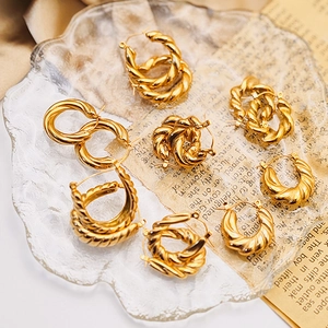 Close-up of golden twist hoop earrings with vintage texture on a decorative glass tray