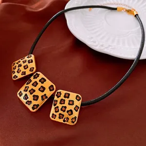 Collier vintage à pendentif léopard carré avec pierres orange sur un fond de soie rouge