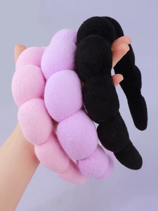 Close-up of thick microfiber spa headbands in pink, light purple, and black colors