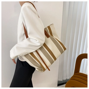 Detailed side view of striped canvas tote bag with brown leather straps on model