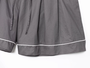 Detailed macro view of dark grey poplin shorts featuring contrast white piped edging