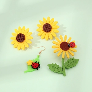 Detailansicht handgefertigter Filz-Sonnenblumen- und Marienkäferohrringe mit Stoffstruktur